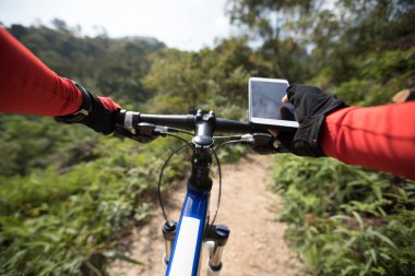 Tepenin üst üste binme, cep telefonu, holding rider Gps aramak için online başvuru kullanarak güneşli günde ormandaki bisiklet sürme sırasında koordinatları 