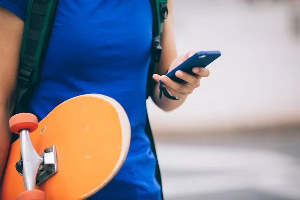 Mladý americký skateboardista pomocí smartphonu — Stock fotografie