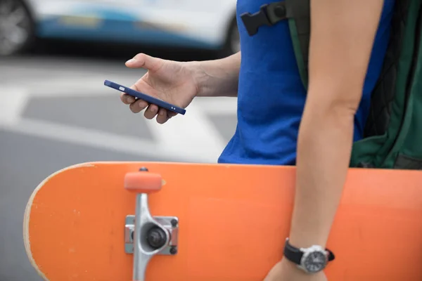 Junge Skateboarder nutzen Smartphone — Stockfoto