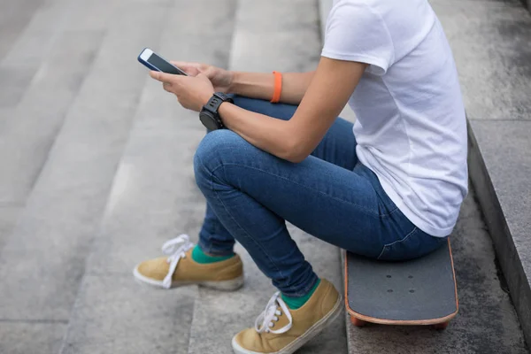 Vrouw Met Behulp Van Smartphone Zittend Het Skateboard Stad Trappen — Stockfoto