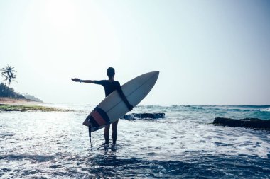 Mutlu kadın sörfçü yosunlu deniz kıyısı üzerinde surfboard ile