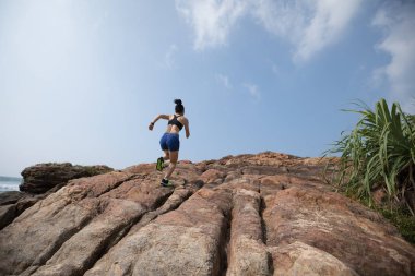 Kayalık dağ üstüne sahil üzerinde çalışan kadın iz runner