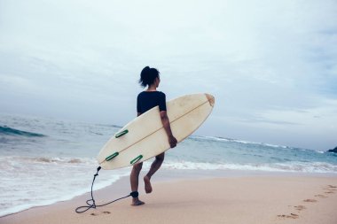 Sörfçü kadın tropik sahilde yürüyüş surfboard ile 