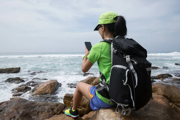 妇女徒步旅行使用手机在海边 — 图库照片