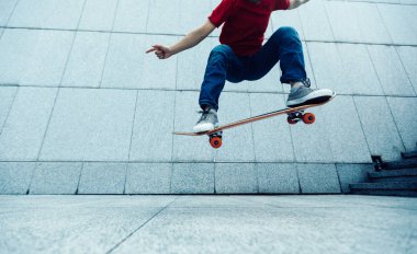 Young skateboarder doing ollie at city clipart
