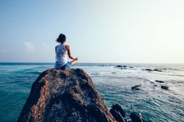 Genç kadın deniz kaya uçurumun kenarında meditasyon 