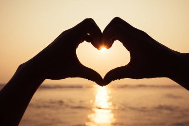 Gün batımı kalbine parlayan el şeklinde