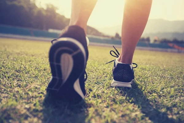 健身女运动员腿在体育场草地上奔跑 — 图库照片