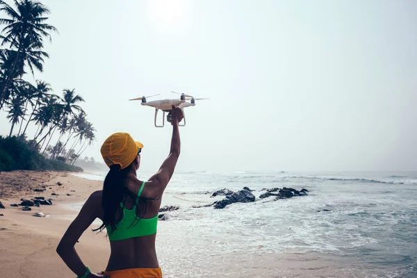 Woman photographer landing or taking off a drone on seaside