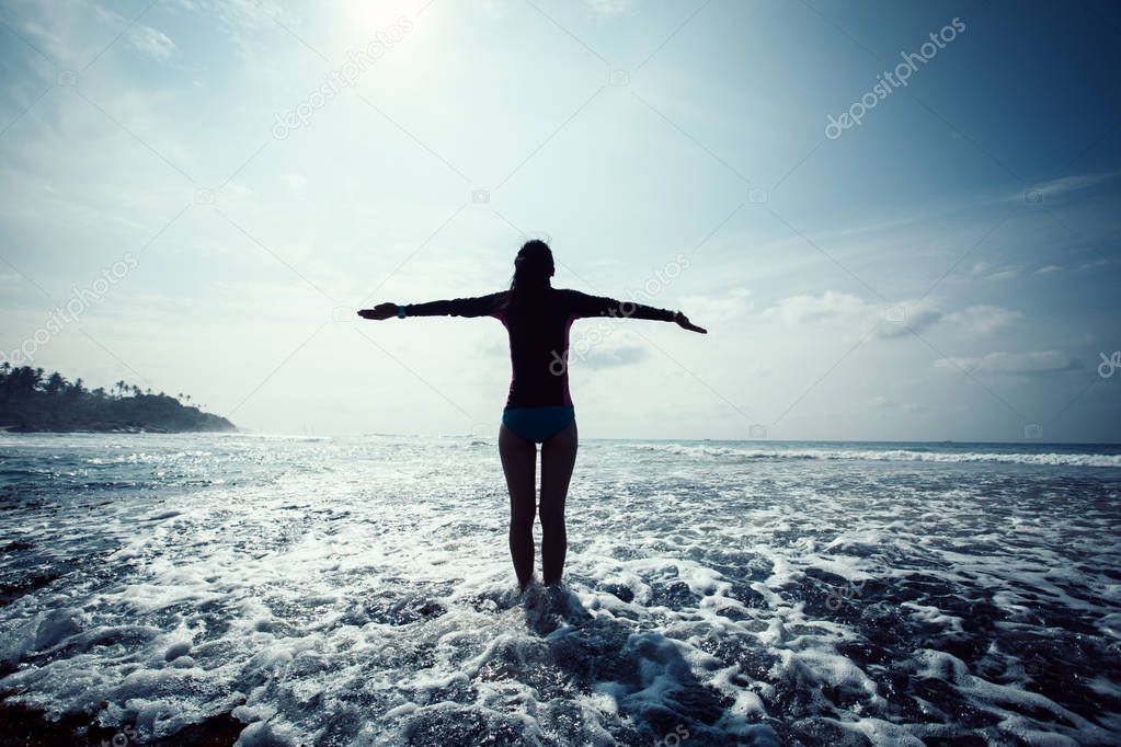 Freedom Woman with outstretched arms at Sunrise seaside reef