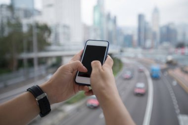 Cep telefonunuzun ve bulanık cityscape arka plan üzerinde eller 