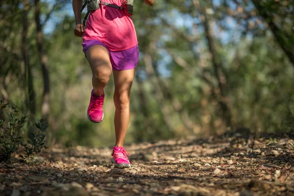 Young woman trail runner running in forest trail