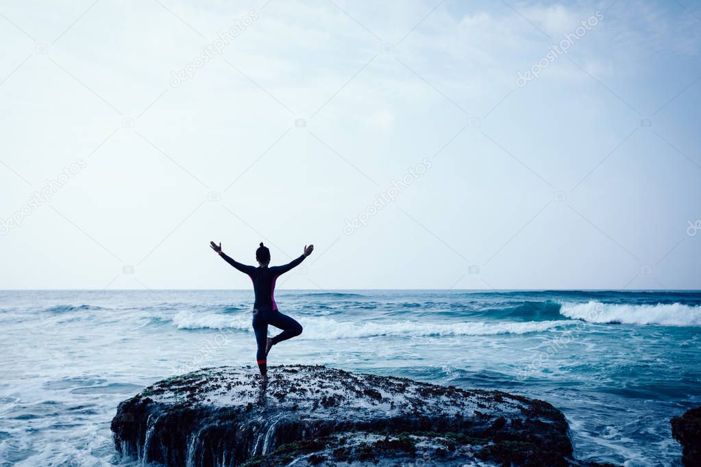 Freedom Woman with outstretched arms at seaside mossy reef