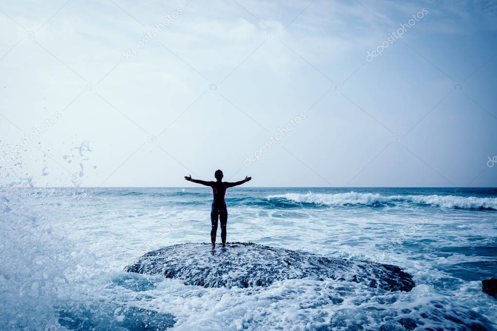 Freedom Woman with outstretched arms at seaside mossy reef