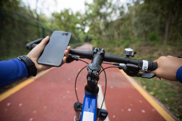 Велосипедист с помощью приложения смартфона для навигации во время езды на велосипеде по лесной тропе
