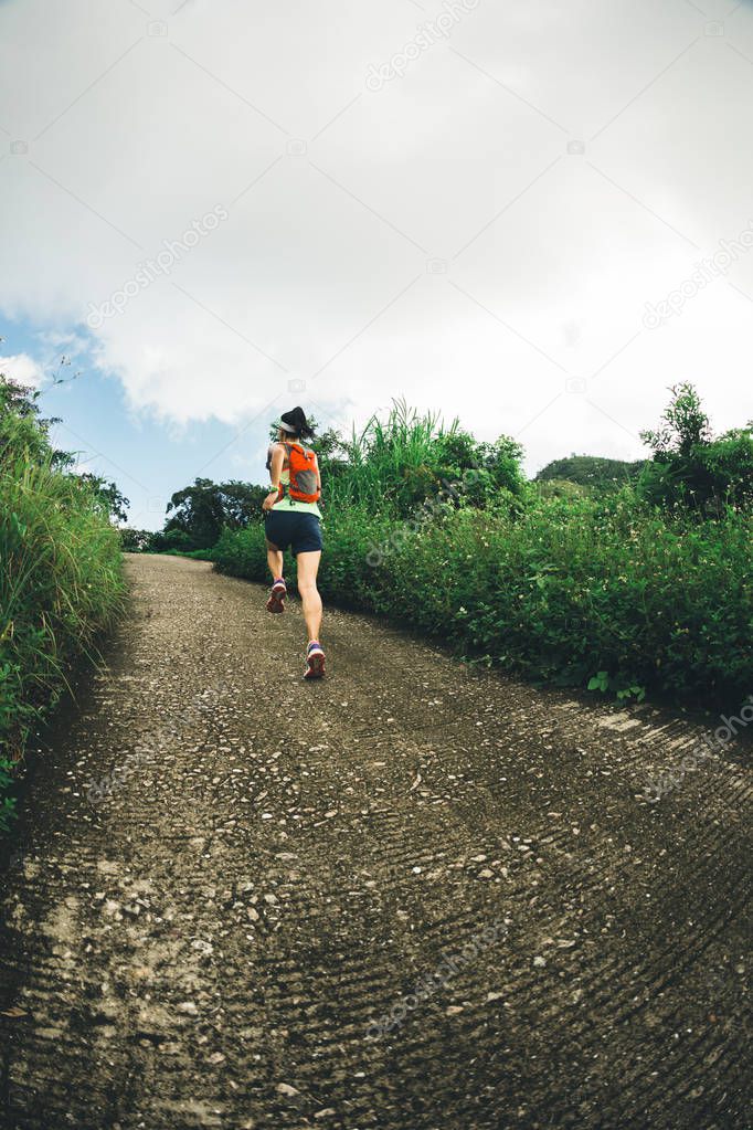 young fitness woman trail runner running to mountain top
