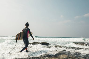 Genç kadın surfer sörf tahtası gidiş ile sörf