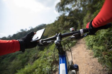 Tepenin üst üste binme, cep telefonu, holding rider Gps aramak için online başvuru kullanarak güneşli günde ormandaki bisiklet sürme sırasında koordinatları 