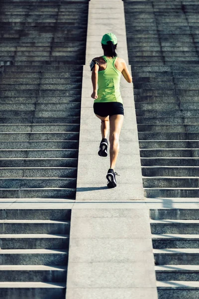 Young woman runner running up on city stairs, jogging and running in urban training workout