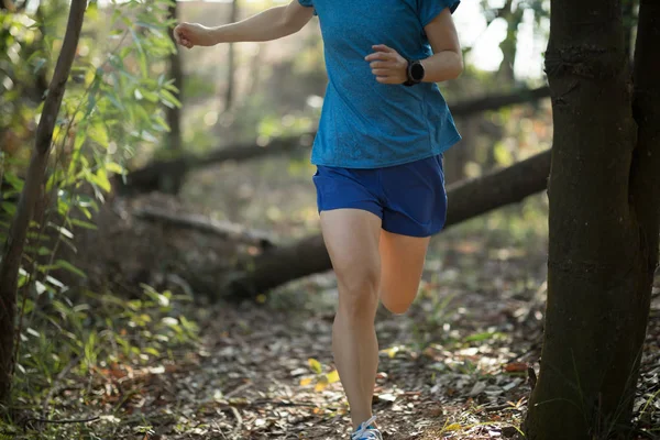 Sportswoman cross country trail running in forest