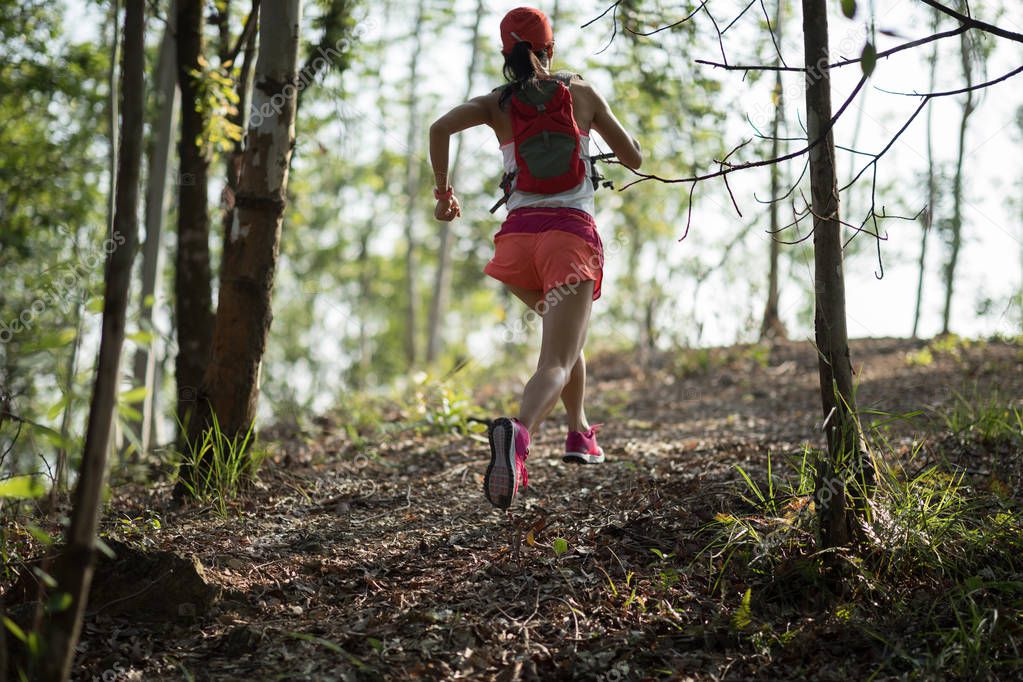 Sportswoman cross country trail running in forest