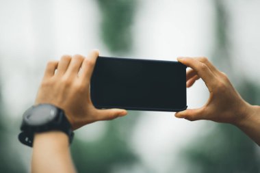 Smartphone alarak fotoğraf için ormanda holding eller