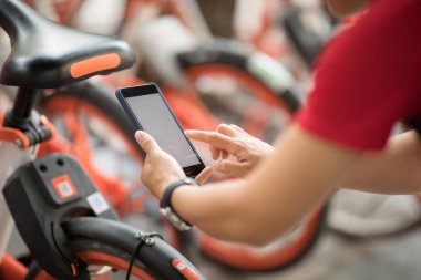 Akıllı telefon kullanan eller, şehirdeki paylaşılan motorun QR kodunu tarıyor