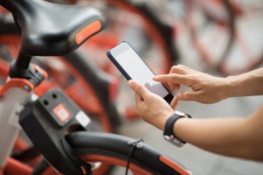 Akıllı telefon kullanan eller, şehirdeki paylaşılan motorun QR kodunu tarıyor