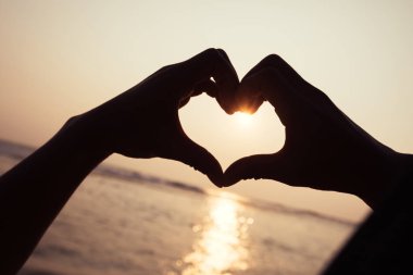 Gün batımı kalbine parlayan el şeklinde