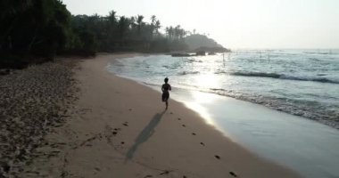 Fitness sağlıklı yaşam konsepti, tropik sahilde sabah gündoğumu sırasında çalışan genç kadın