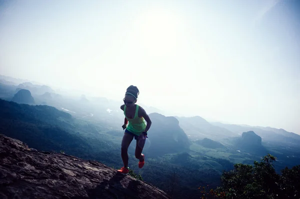年轻的健身女子跟踪跑在山顶悬崖边 — 图库照片