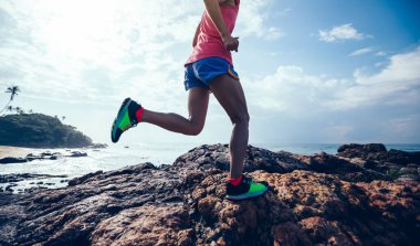 Kayalık dağ üstüne sahil üzerinde çalışan genç fitness kadın iz runner