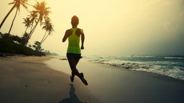 Fitness sağlıklı yaşam konsepti, tropik sahilde sabah gündoğumu sırasında çalışan genç kadın