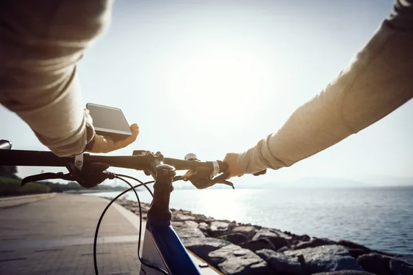 Cyclist using smartphone for navigation when riding mountain bike on the coast path