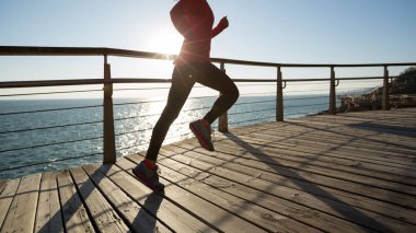 Sahil sahil gündoğumu sırasında sportif kadın koşucu sabah egzersiz