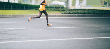 Şehir yolunda koşan maraton koşucusu bacakları
