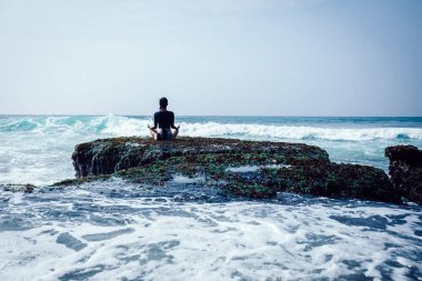 Önümüzdeki güçlü deniz dalgaları karşı karşıya sahil mercan uçurumun kenarında meditasyon kadın