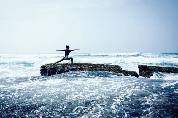 在海边珊瑚悬崖边练习瑜伽的年轻女子 — 图库照片