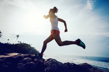 Kayalık dağ üstüne sahil üzerinde çalışan genç fitness kadın iz runner