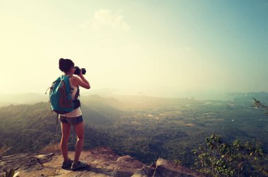 Genç bayan fotoğrafçı dağ zirvesinde fotoğraf çekiyor.