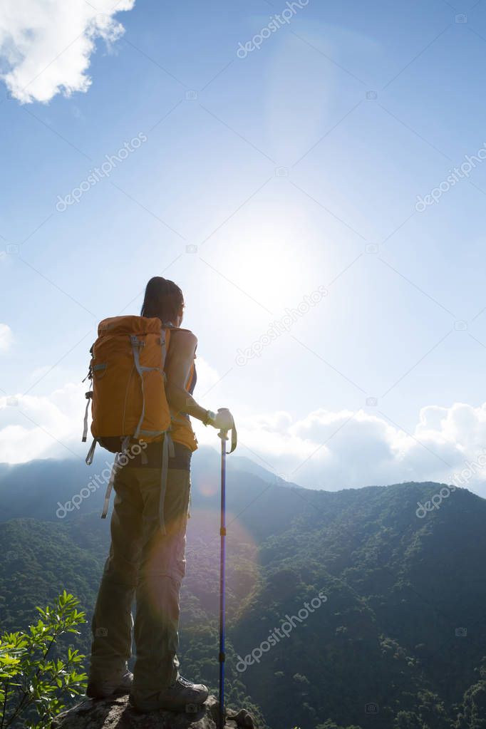 Successful woman hiker enjoying the view at mountain peak