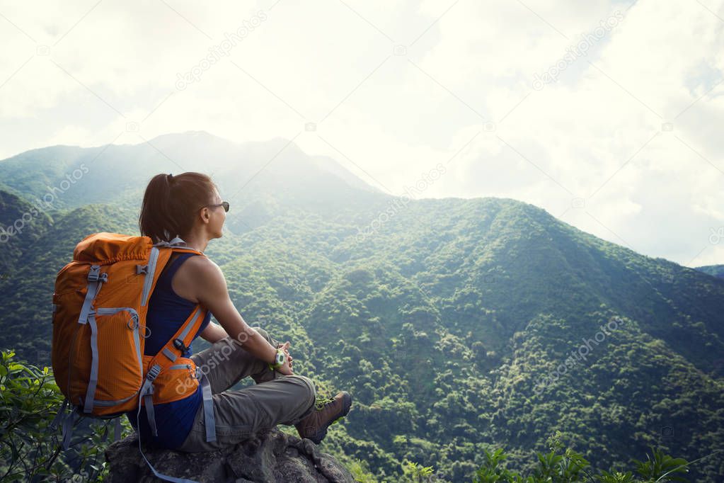 Successful woman hiker enjoying the view at mountain peak