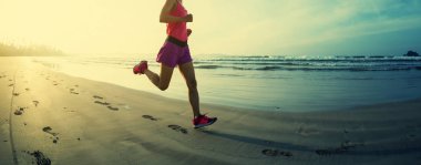 Güneş doğarken plajda koşan fitness kadın koşucusu 