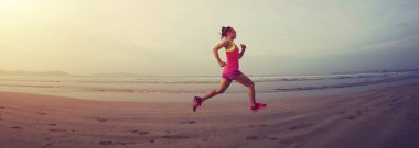 Güneş doğarken plajda koşan fitness kadın koşucusu 
