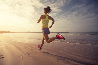 young fitness woman running at sunrise on beach 