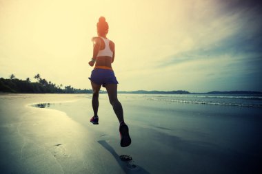 young fitness woman running at sunrise on beach 