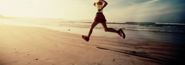 Güneş doğarken plajda koşan fitness kadın koşucusu 