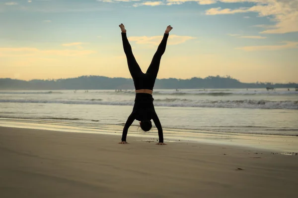 Женщина Тренируется Стоять Руках Океана Восходе Солнца — стоковое фото
