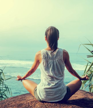 Kaya üzerinde sahilde Yoga pratik kadın 