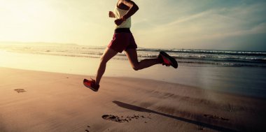 Güneş doğarken plajda koşan fitness kadın koşucusu 